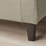 Nahaufnahme eines stilvollen Sofabeins. Robustes, dunkles Holzfinish. Strukturierter, neutraler Stoff.