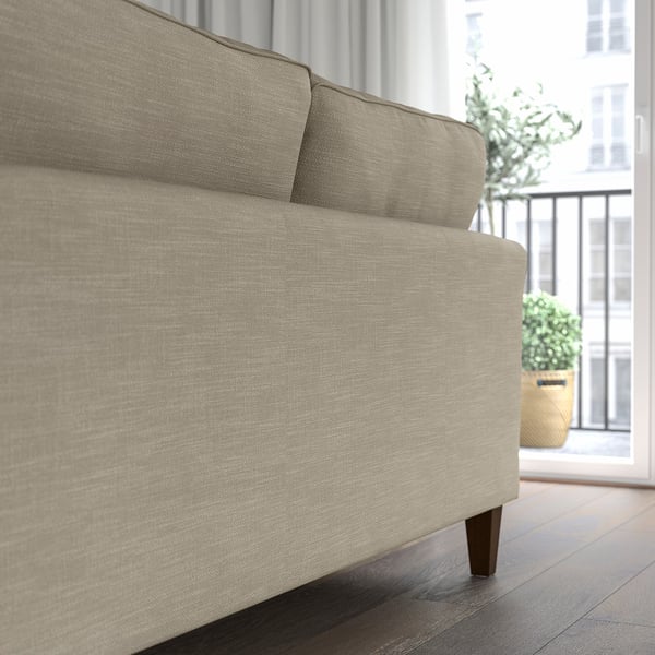 Ein beiges EKHOLMA-Sofa mit Taschenfedern für mehr Komfort, das in der Nähe eines Fensters platziert wird. Der angepasste Bezug ist waschbar und gewährleistet eine einfache Wartung.