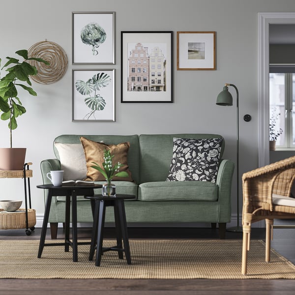 Modernes Wohnzimmer mit grünem EKHOLMA-Sofa, Kissen und Pflanzen.