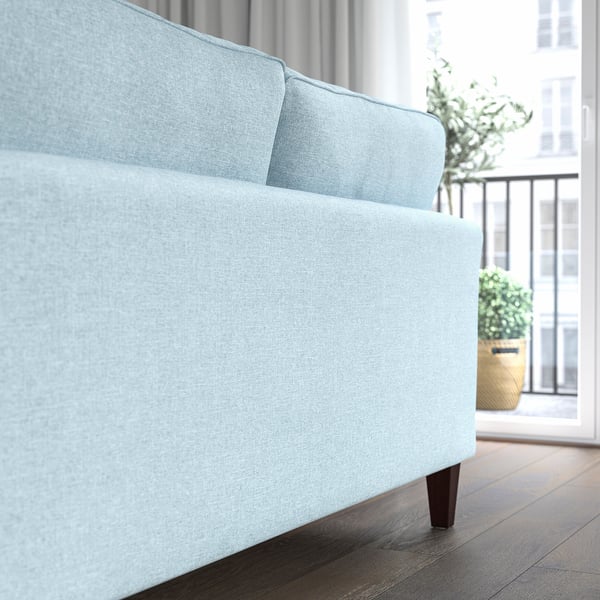 Hellblaues Sofa mit Holzbeinen, in der Nähe von Fenstern und Pflanzen, bietet Komfort mit Taschenfedern und abnehmbarem Bezug.