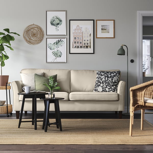 Gemütliches Wohnzimmer mit EKHOLMA-Sofa, grünen Kissen, Couchtisch, Pflanze, Stehlampe und Wanddekoration.