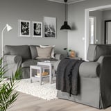 Modernes Wohnzimmer mit EKTORP-Sofas, Wurfdecke, Kissen, Couchtisch, Lampe, Kunst und einer Pflanze.
