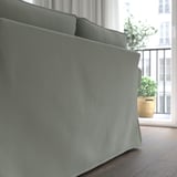 Graues EKTORP-Sofa in der Nähe des Fensters, mit Blick auf die Stadt. Kuschelige, dicke Kissen.