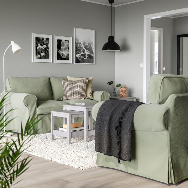 Gemütliches Wohnzimmer mit hellgrünen EKTORP-Sofas, Schwarz-Weiß-Kunstwerken und einer schwarzen Pendelleuchte, die einen modernen und dennoch einladenden Raum schaffen.