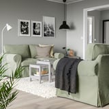 Gemütliches Wohnzimmer mit hellgrünen EKTORP-Sofas, Schwarz-Weiß-Kunstwerken und einer schwarzen Pendelleuchte, die einen modernen und dennoch einladenden Raum schaffen.