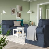 Helles Wohnzimmer mit blauem EKTORP-Sofa und Sessel, weißem Couchtisch, grünen Wänden. Sofa und Sessel haben dicke, wendbare Kissen.