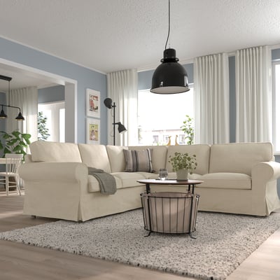 Beige EKTORP Sektion, weiche Kissen. Modernes Wohnzimmer mit Teppich, Holzboden, Industrielampe, Pflanzen.