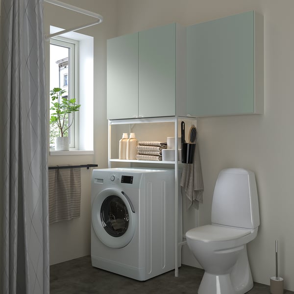 Modernes Wäschereizentrum ENHET mit grünem Stauraum. Frontlader-Waschmaschine, offene und geschlossene Schränke, schlanker Toilettenschrank.