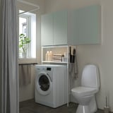 Modernes Wäschereizentrum ENHET mit grünem Stauraum. Frontlader-Waschmaschine, offene und geschlossene Schränke, schlanker Toilettenschrank.