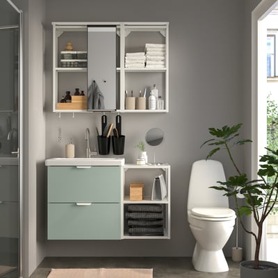 Modernes Badezimmer mit blauem Schrank, Spiegel, WC und Pflanze.