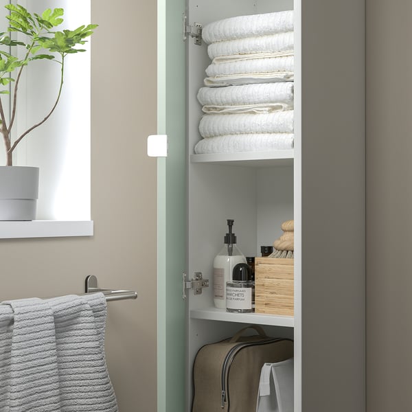 Aufbewahrungsschrank mit Handtüchern, Toilettenartikeln und Taschen. Grau-grüne Ästhetik.