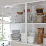 Moderne Küchenregale zeigen durchsichtige Gläser, Teller, Schüsseln und Holzbehälter, in denen Küchenutensilien ausgestellt sind.