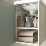 Offener Badezimmerschrank mit Handtüchern, Kosmetiktasche und Toilettenartikeln, die darin aufbewahrt werden.
