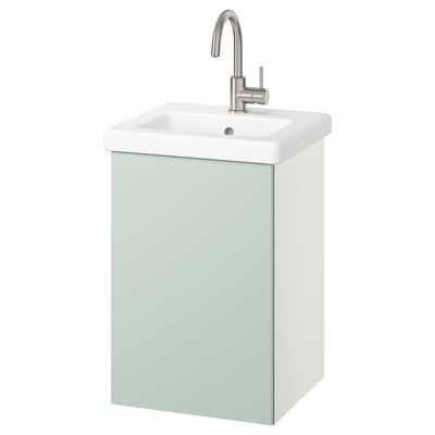 Ein hellgrüner Wandschrank mit weißem Waschbecken und silbernem Wasserhahn.