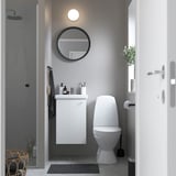 Modernes Badezimmer mit weißem ENHET-Schrank, Waschbecken, WC und rundem Spiegel darüber. Kompakt und platzsparend.