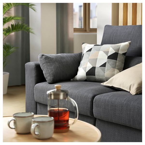 Ein gemütliches graues Stoffsofa mit gemusterten Kissen und einem Holztablett mit einem Teeservice.