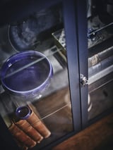 Glastürschrank FABRIKÖR mit blauer Schale, Schlüsseln und Büchern, mit verstellbaren Einlegeböden und Türschloss mit Metallschlüsseln.