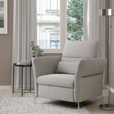 Moderner grauer FAMMARP-Sessel mit verstellbaren Armlehnen und Kopfstütze, gemütliches Wohnzimmer, Pflanze, Becher, Lampe, Teppich.