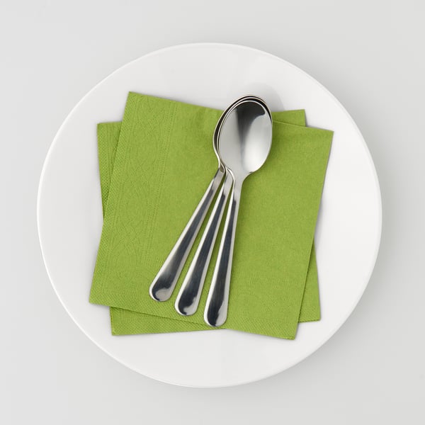 Ein Teller mit grünen Papierservietten und drei Metalllöffeln. Servietten sind saugfähig und dekorativ für den gedeckten Tisch.