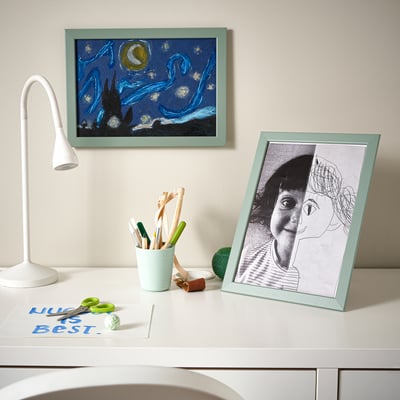 Schreibtisch mit Malutensilien, zwei Zeichnungen: eine Schwarz-Weiß-Skizze, ein blauer Nachthimmel, Lampe.