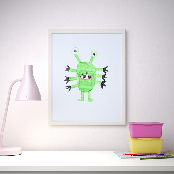 Gerahmte Kindermonsterkunst hängt über einem Schreibtisch mit einer Lampe und Aufbewahrungsbehältern und zeigt weiche Linien und einen sicheren Frontschutz aus Kunststoff.