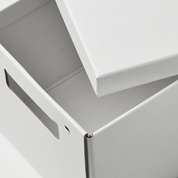 Geschlossener weißer Karton, sauber gefertigt mit sichtbarem Metallverschluss, auf einer ebenen Fläche sitzend.