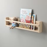 In einem Wandregal aus Holz befinden sich ein Teddybär und Kinderbücher. Die offene Front ermöglicht einen einfachen Einstieg für Kinder.