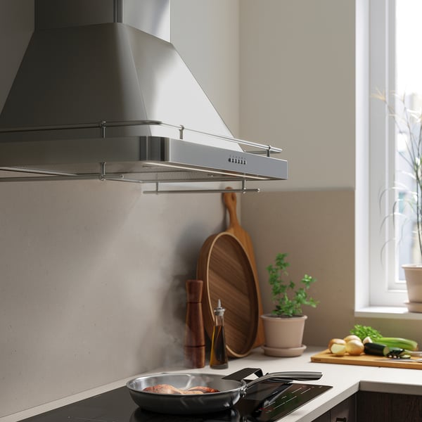 Moderne Küche mit rostfreier FÖLJANDE-Dunstabzugshaube, LED-Leuchten und Kochpfanne.