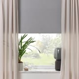 Fenster mit grauem Rollo, durchsichtigen Vorhängen, Pflanze, Vase und Lautsprecher auf der Fensterbank bieten Lichtblock und modernes Dekor.