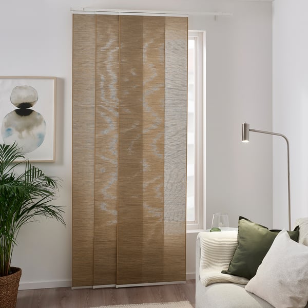 Modernes Zimmer mit großem FÖNSTERVIVA Paneelvorhang in beige-braun, füllendes Fenster; Weiße Couch mit grünen Kissen, Lampe, Pflanze, abstraktes Gemälde.