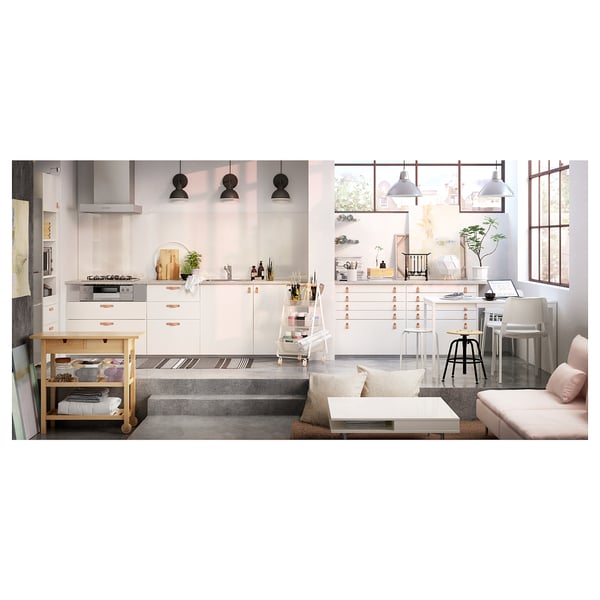 Moderne, helle Küche mit weißen Schränken, eleganten Geräten, Holzinsel und hellrosa Sofa.
