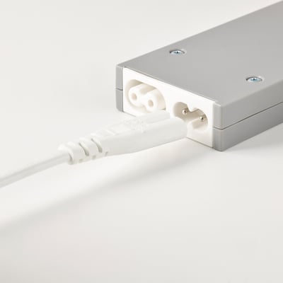 Ein silbernes Netzteil, das an einen weißen Stecker und ein weißes Kabel angeschlossen ist und für den Anschluss der Netzlampe mit drahtloser Steuerung verwendet wird.