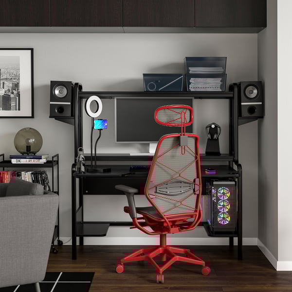 Moderne Büroeinrichtung mit rotem Gaming-Stuhl, schwarzem Schreibtisch, Lautsprechern und Monitor.