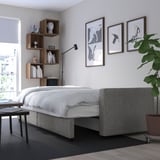 Minimalistisches Schlafzimmer mit ausziehbarem Bett, eingebautem Stauraum und Wandkunst.