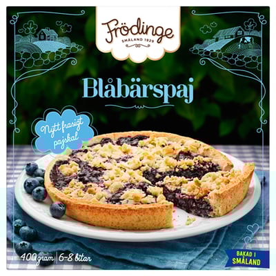 Bildbeschreibung: FRÖDINGE Heidelbeerkuchen Werbung. Zeigt Kuchen auf dem Teller mit frischen Blaubeeren.