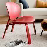 Hellroter stilvoller Stuhl in der Nähe der cremefarbenen Couch, modernes minimalistisches Design, Holzrahmen.