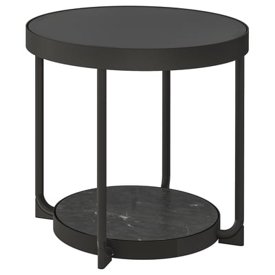 Ein schlanker, schwarzer runder Beistelltisch mit einer Glasplatte und einer Ablage in Marmoroptik, die von vier schlanken Metallbeinen getragen wird. Modernes und minimalistisches Design.
