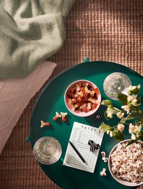 Ein gemütliches Outdoor-Setup mit Popcorn, Gummibonbons und einem Spiel auf einem grünen Tablett.