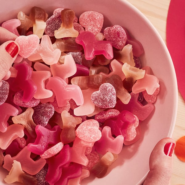 Eine Schüssel mit bunten Gummibonbons in Form von Sternen, Herzen und Elchen in Rot-, Rosa- und Orangetönen.