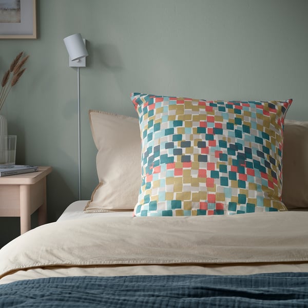 Bett mit GAFFELBRÄKEN Kissen, mehrfarbige Quadrate. Weiche Baumwolle, 65x65 cm, helle Wand.