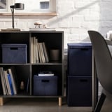 Minimalistisches Homeoffice mit GJÄTTA Aufbewahrungsboxen aus blauem Samt, Büchern und eleganten Möbeln.