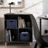 Gemütliches Home Office mit blauer Samt-GJÄTTA-Box auf dem Regal, beleuchtet von einer Schreibtischlampe.
