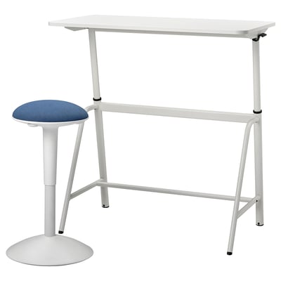 Ein weißer Sitz-Steh-Schreibtisch und ein blauer Hocker mit gepolsterter Sitzfläche. Der Schreibtisch lässt sich in der Höhe verstellen und der Hocker bietet bequeme Sitzgelegenheiten.