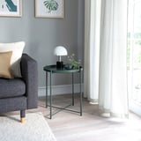 Kleiner dunkelgrüner Beistelltisch mit runder Tablettplatte neben grauer Couch unter weißer Lampe.