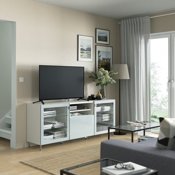 Modernes Wohnzimmer mit blauem TV-Ständer, Glastüren, Bildern und Lampe. Großes Fenster schafft eine gemütliche Atmosphäre.
