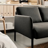 Ein modernes graues Sofa, GLOSTAD, mit schlanken Metallbeinen, die bequeme Sitzgelegenheiten bieten. Das Sofa hat ein minimalistisches Design, das für kleine Räume geeignet ist.