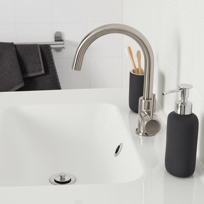 Modernes Waschbecken mit GLYPEN Edelstahlarmatur, schwarzen Accessoires, schlankem Design.