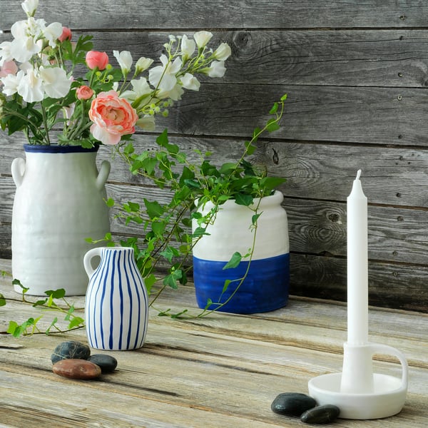 Holzhintergrund mit drei Vasen mit Blumen und Kerze, natürliches Dekor.