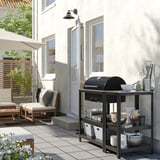 Außenterrasse mit GRILLSKÄR Grillinsel, Holzkohlegrill, Sitzgelegenheiten und Esszubehör.