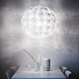 Moderne Esseinrichtung mit weißer Hängelampe, die sanftes Licht ausstrahlt, umgeben von verschiedenen weißen Vasen auf dem Tisch.